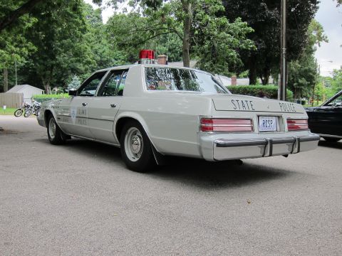 1991 Ford LTD Crown Victoria - Rear three-quarter view of a silver Rhode Island State Police sedan with a red roof beacon and a RISP rear plate.
