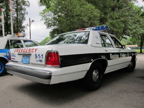 1991 Ford LTD Crown Victoria - Rear three-quarter view of a white-and-black Boston Police Ford sedan with EMERGENCY CALL 9-1-1 lettering and roof lightbar.