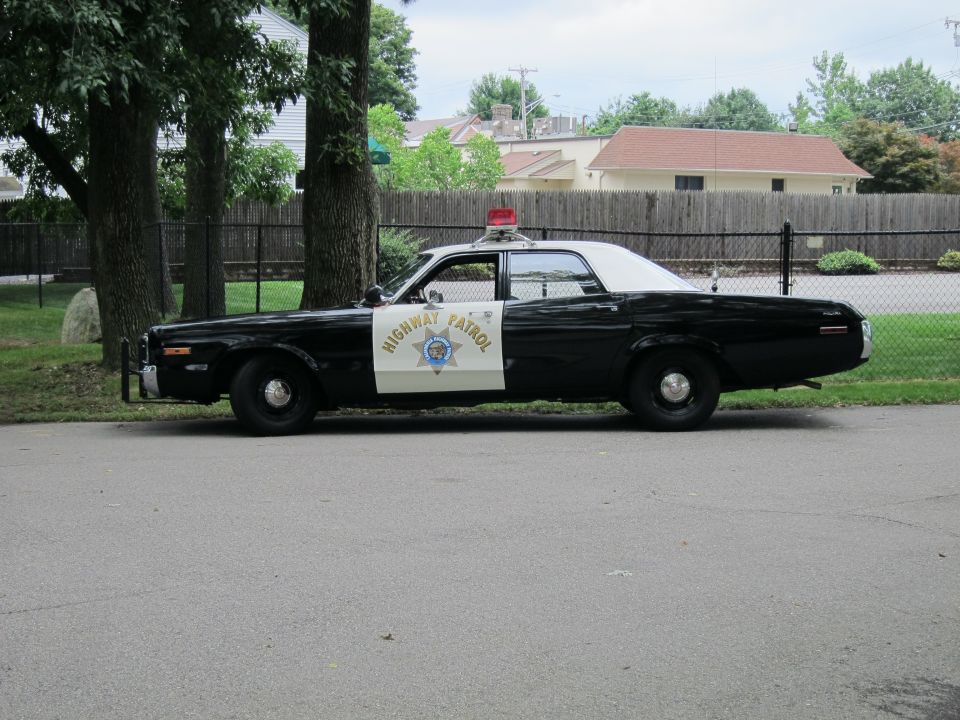 Black and white Highway Patrol sedan with white roof, driver side profile