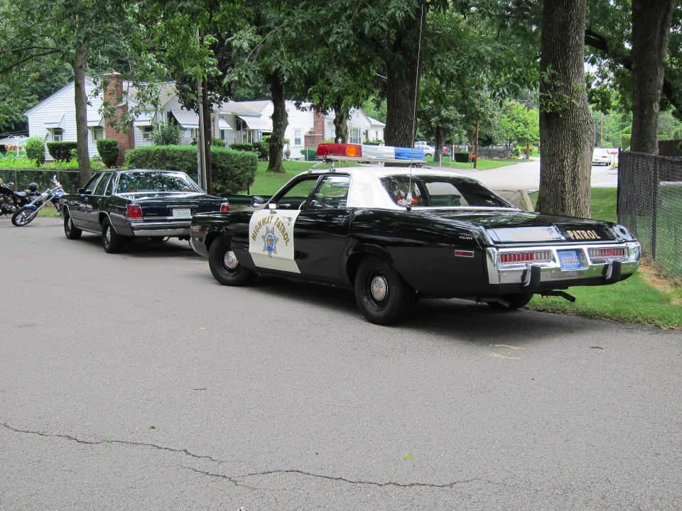 Black and white Highway Patrol sedan and dark sedan parked in a row