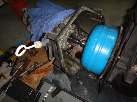 1994 Ford Bronco - A disassembled transmission and torque converter are laid out on a workbench with various tools scattered around.