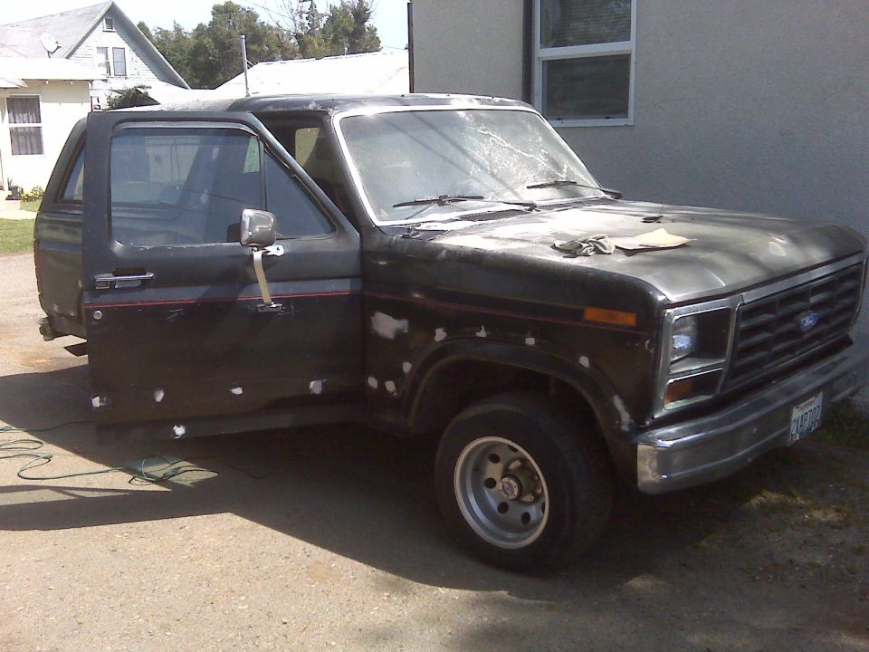 1980 Ford Bronco with doors open, showing bodywork prep. The rear quarter panel is missing