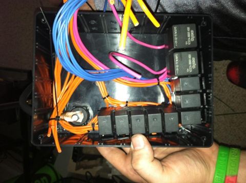 1991 Ford F-250 - A hand holds a black plastic automotive relay box filled with colorful wires and black relays.