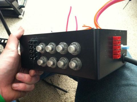 1991 Ford F-250 - A hand holds a black breaker box multiple silver switches and red electrical connectors with wires protruding.