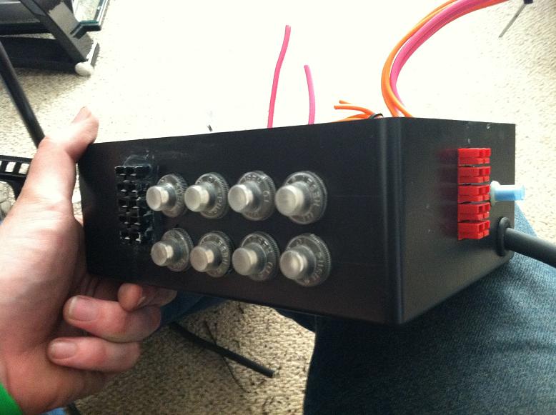 Black breaker box with eight silver switches and red connectors