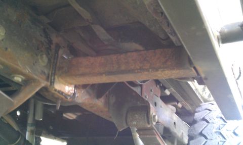 1995 Ford Bronco - Close-up view of the undercarriage, showing rusted frame components and suspension parts.