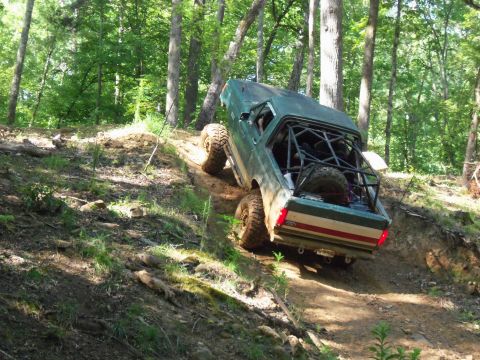 1987 Ford F-250 - This modified pickup truck is navigating a steep, wooded trail.