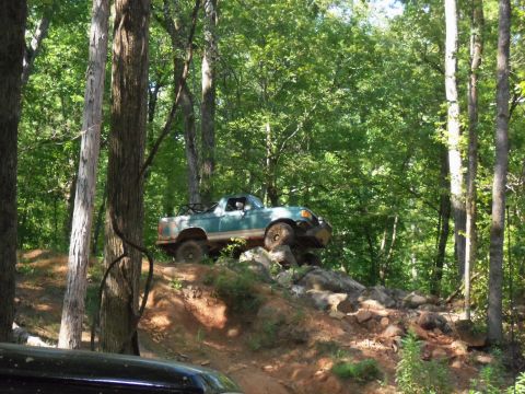 1987 Ford F-250 - This 1987 Ford F-250 navigates a challenging rocky incline in a forest setting.