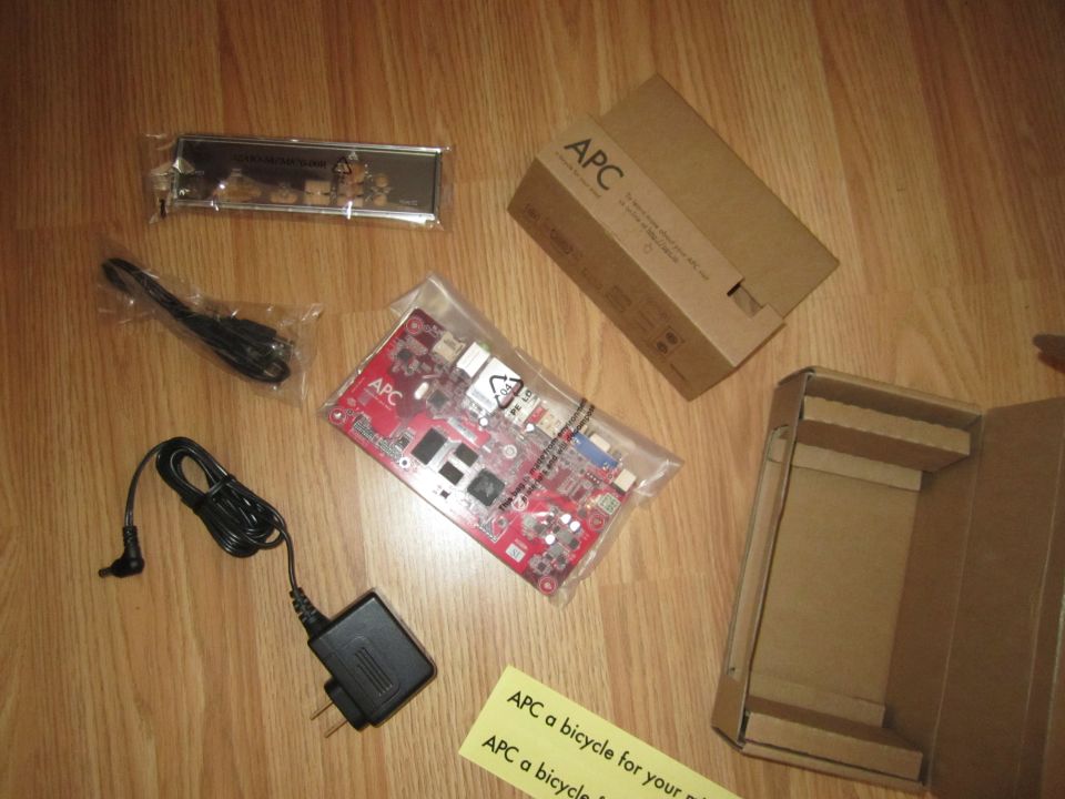 APC computer board, power adapter, cables, and boxes on a wooden floor