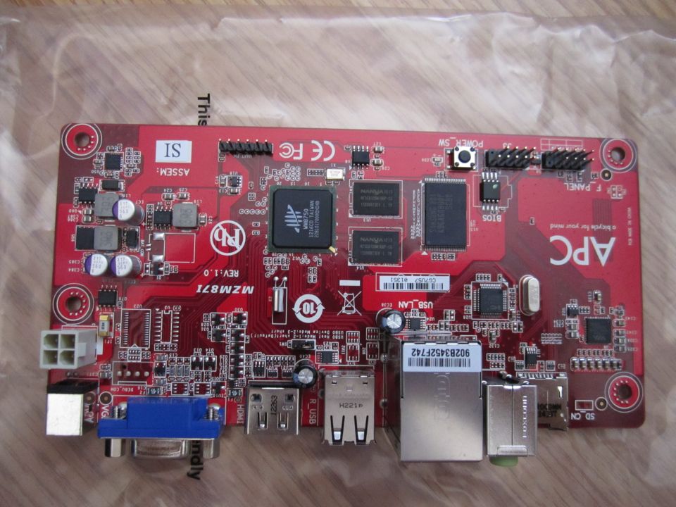 Red APC motherboard with various chips, ports like VGA, USB, and Ethernet