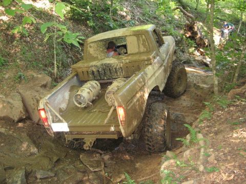 1979 Ford F-150 - A heavily mud-splattered 1973 Ford F-150 navigates a challenging off-road course with another vehicle visible in the background.