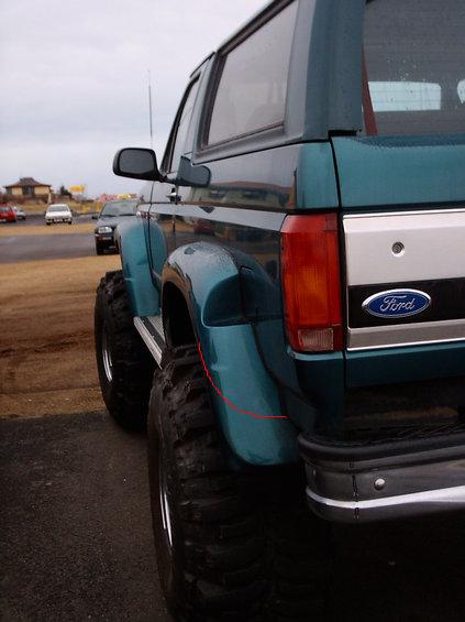 1995 Ford Bronco - Rear view of a teal 1995 Ford Bronco, modified with oversized tires and a lifted suspension.