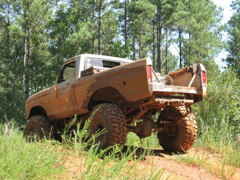 1979 Ford F-150 - Muddy 1979 Ford F-150 pickup truck with lifted suspension and large tires parked off-road.
