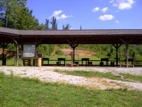 1982 Ford Bronco - A covered shooting range with multiple benches and targets set against a backdrop of trees and a blue sky.