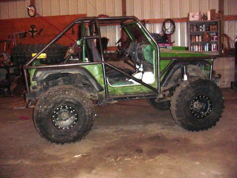 1992 Ford Bronco - Customized off-road vehicle with a prominent roll cage and oversized tires is shown in a garage setting.