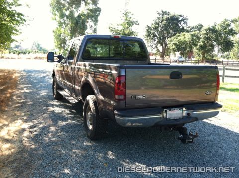 2003 Ford F-250 - This Ford F-250 pickup truck is shown from the rear on a gravel surface with trees in the background.