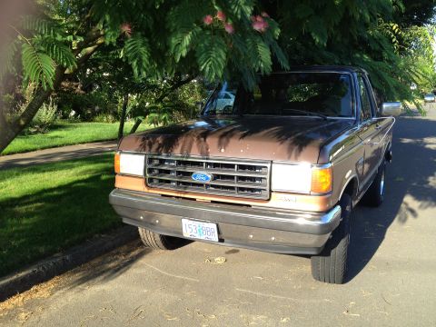 1991 Ford Bronco - Front view of a brown and tan 1987 Ford F-150 parked on a residential street.