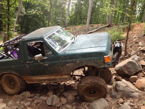 1979 Ford F-150 - A modified green truck navigates a challenging, rocky off-road path.