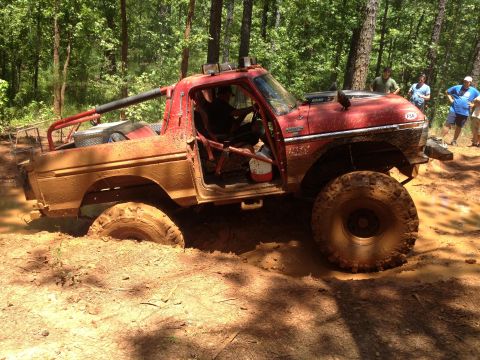 1979 Ford F-150 - A red 1979 Ford F-150 is deeply stuck in mud during an off-road event.