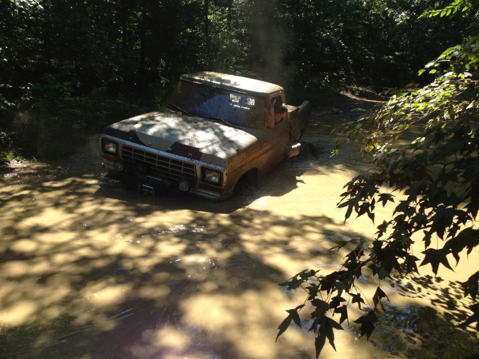 1979 Ford F-150 stuck in mud and water, front grille and winch visible