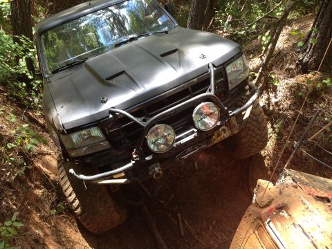 1979 Ford F-150 - This truck is navigating a challenging off-road course, getting stuck in the mud on a steep incline.