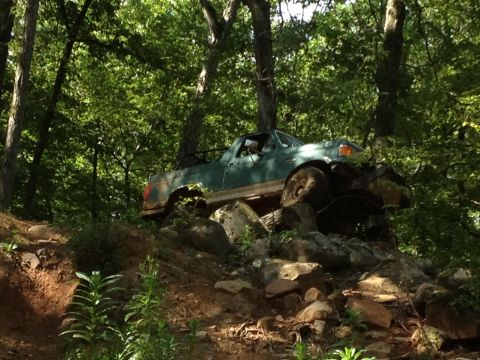1979 Ford F-150 - A green pickup truck navigates a rocky incline in a wooded area.