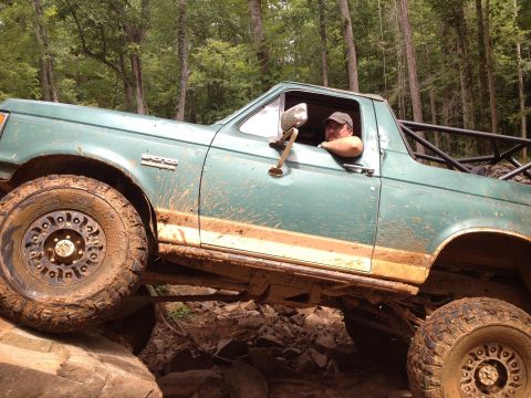 1979 Ford F-150 - Ford Bronco navigating difficult terrain on a wooded trail.