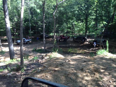 1979 Ford F-150 - Multiple off-road vehicles are gathered in a wooded area, with a silver pickup truck among them.