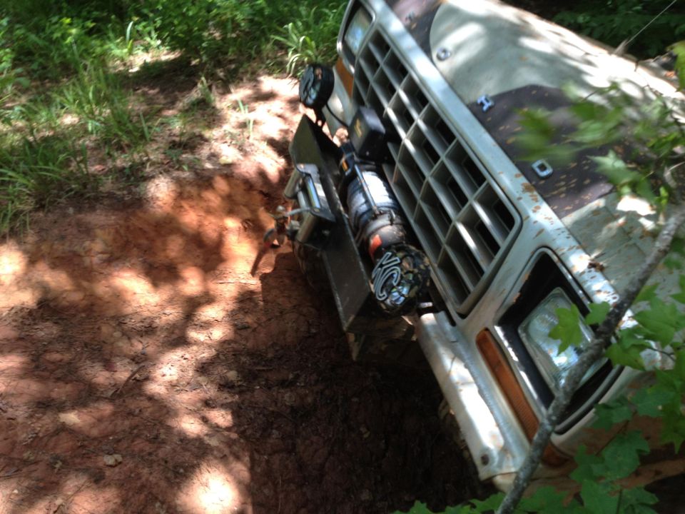 1979 Ford F-150 truck with winch mounted on front bumper, angled view on muddy terrain