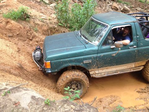 1979 Ford F-150 - Ford Bronco navigating a muddy off-road trail with a winch engaged.