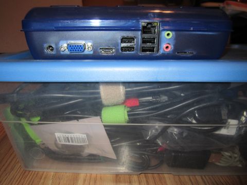 1963 Ford Falcon - A blue electronic device with various ports is shown, resting on a blue plastic container filled with cables.