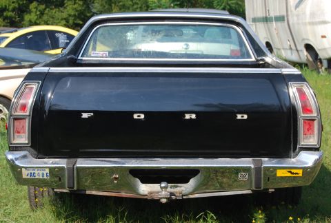 1975 Ford Ranchero - Rear view of a black 1975 Ford Ranchero, the 'FORD' lettering on the tailgate and a chrome bumper with a trailer hitch.