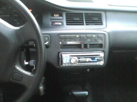 2003 Ford Crown Victoria - The interior of a vehicle shows the dashboard, steering wheel, and an aftermarket stereo system with a digital clock displaying 2:27.