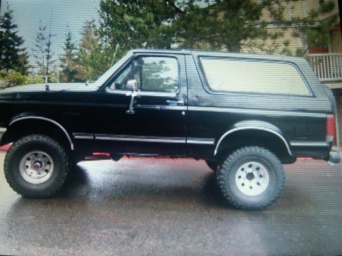 1987 Ford Bronco - Side view of a black 1987 Ford Bronco with aftermarket wheels and lifted suspension.