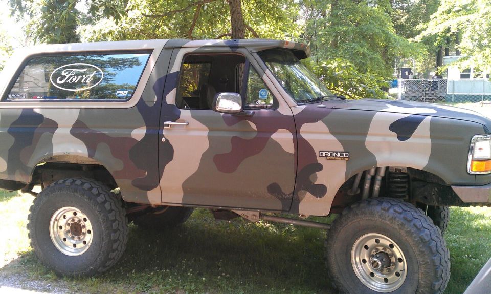 1995 Ford Bronco with camouflage paint, lifted suspension, and aftermarket wheels