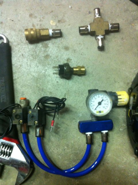 1989 Ford Bronco - Various air suspension parts are laid out on a concrete floor, including a pressure gauge and solenoids.