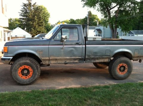 1991 Ford F-250 - This 1991 Ford F-250 pickup truck features a two-tone gray paint scheme and distinctive orange-colored wheel rims.
