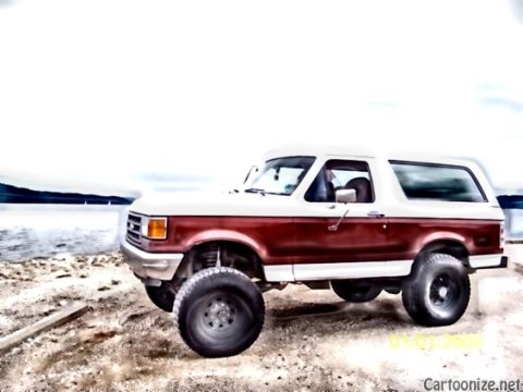 1989 Ford Bronco - A lifted Ford Bronco sits on a sandy shore with a body of water and hills in the background.