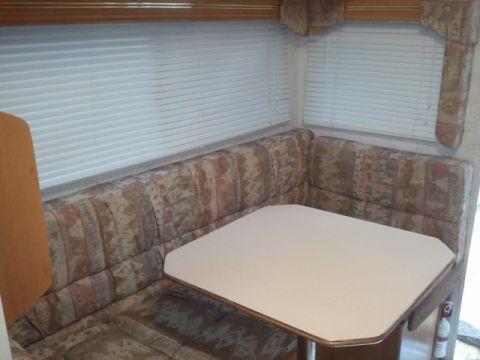 1967 Ford Mustang - The interior of an RV shows a dinette area with upholstered seating and blinds on the windows.