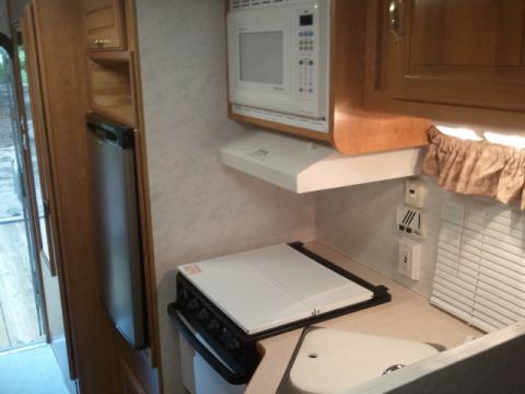 1967 Ford Mustang - The interior of an RV shows a compact kitchen area with appliances and cabinetry.