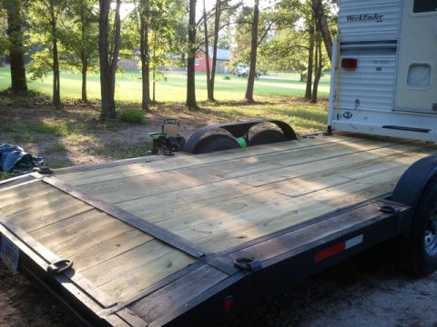 1967 Ford Mustang - A flatbed trailer is parked in a grassy area with trees. A camper is attached to the rear of the trailer.