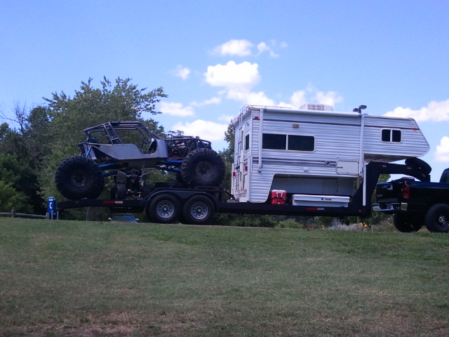 Tube-chassis rock buggy loaded on trailer towed behind a slide-in truck camper