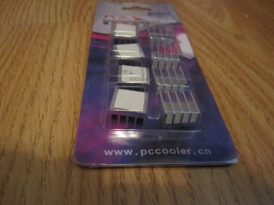 Package of aluminum heatsinks with adhesive backing on a wooden surface