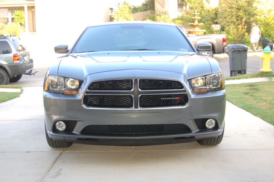 Gray Dodge Charger parked in driveway, front view. SUV in background