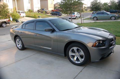 2012 Dodge Charger - A gray Dodge Charger is parked on a suburban driveway with other vehicles and houses in the background.