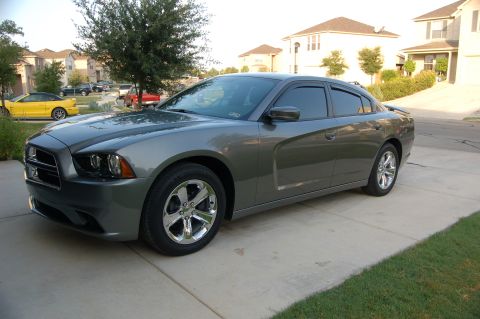 2012 Dodge Charger - A gray sedan is parked on a concrete driveway with a yellow car visible in the background.
