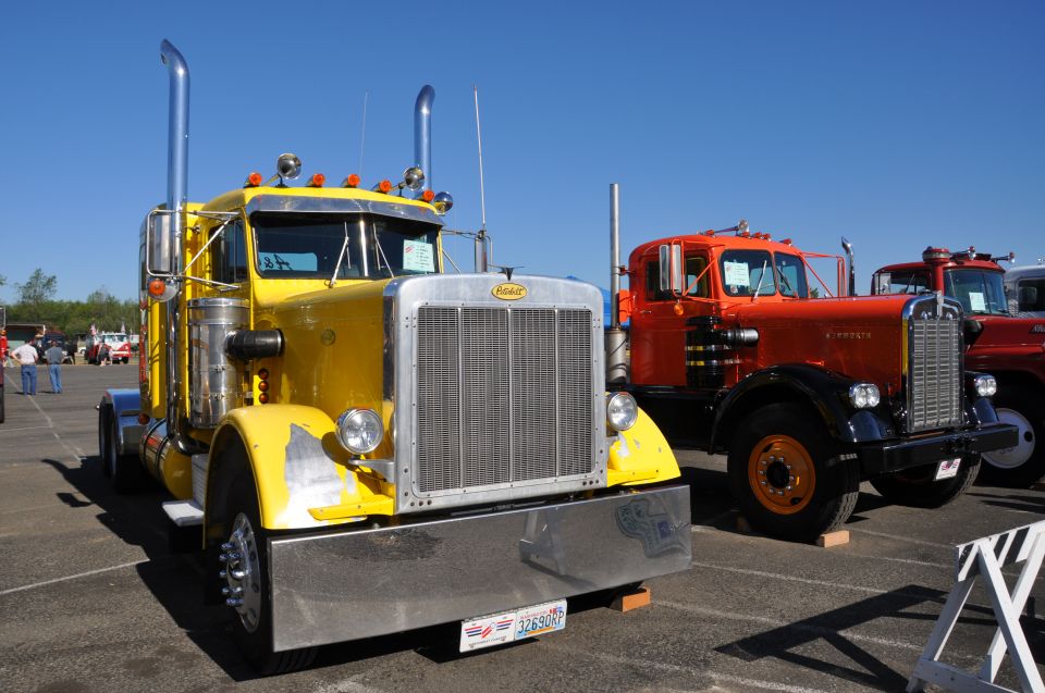 Yellow Peterbilt and orange truck parked outside on a sunny day