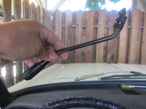 1964 Ford Ranchero - A hand holds a bent metal rod with a ribbed black handle, likely a broken vehicle part.