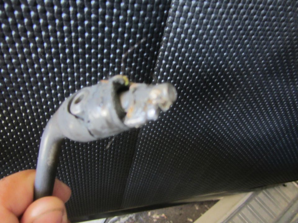 Close-up of a broken metal shifter lever held by a hand against a black textured surface