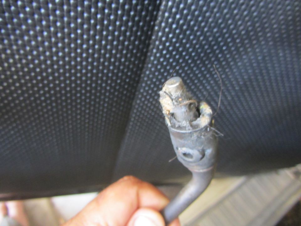 Broken shifter cable held by hand against textured black surface